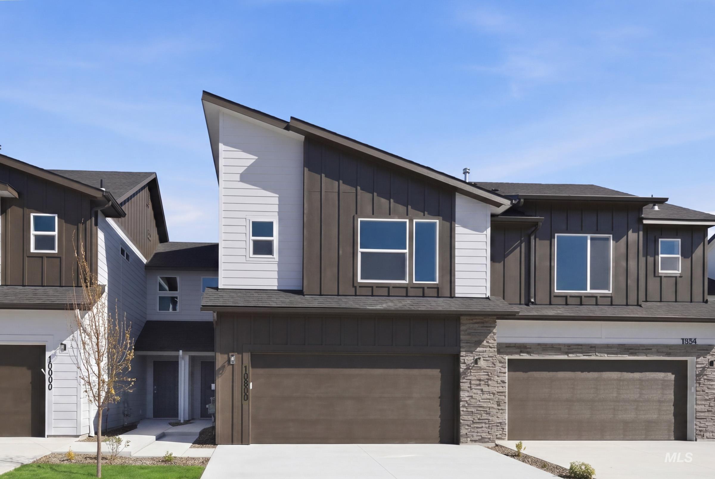 10800 Rutland Street Caldwell, ID 83605 - Photo 1 of 21 Modern exterior featuring a prominent angled roofline, vertical and horizontal siding, stone accents, multiple large windows, and an attached garage