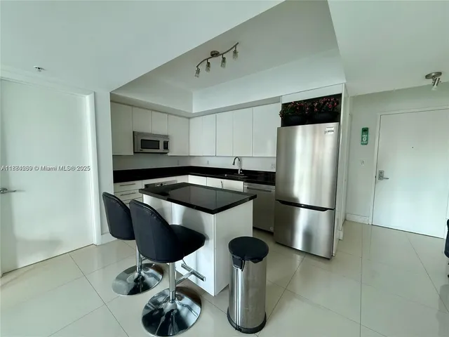 a kitchen with stainless steel appliances kitchen island granite countertop a refrigerator a stove a sink dishwasher and white countertops with wooden floor