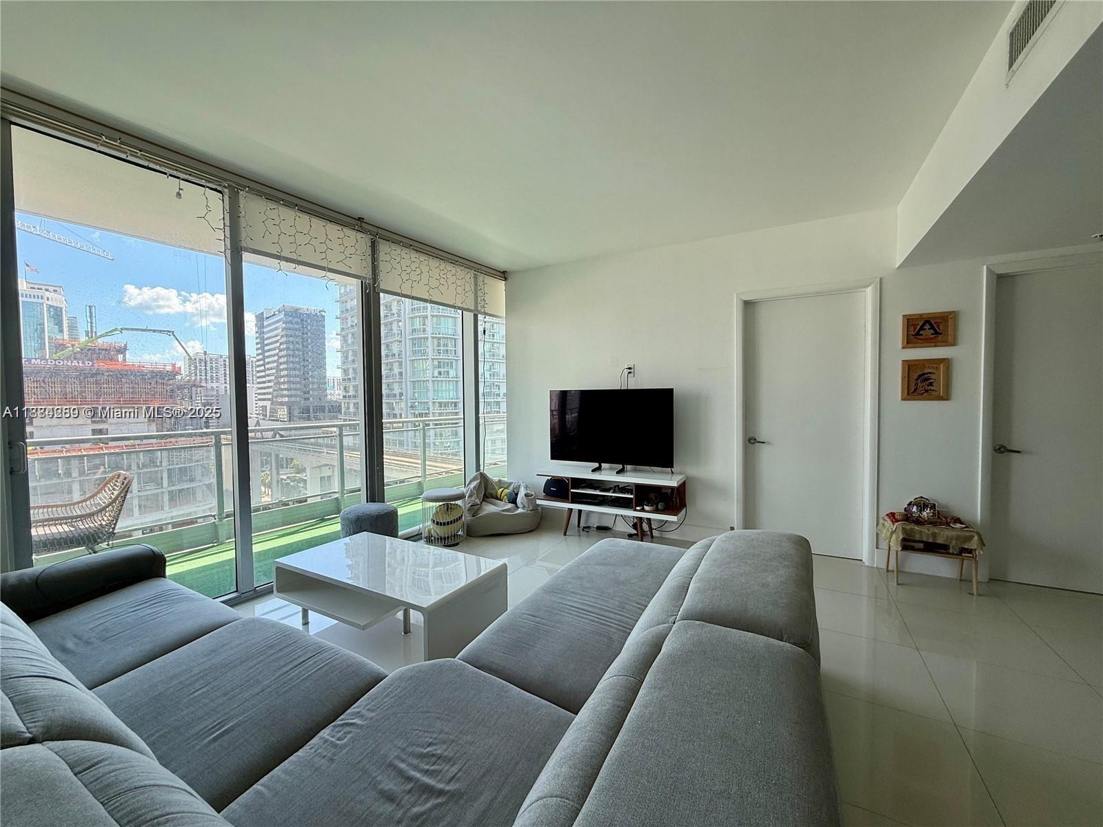 92 Southwest 3rd Street, Unit 1104 Miami, FL 33130 - Photo 4 of 17 a living room with furniture a flat screen tv and floor to ceiling window