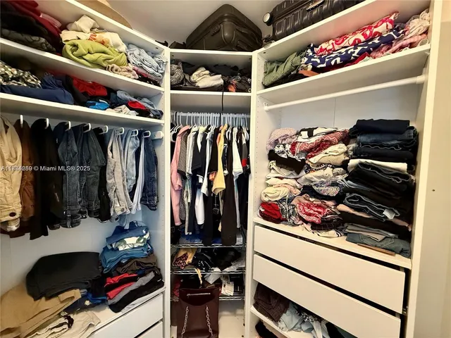 a view of walk in closet with clothes and shoes