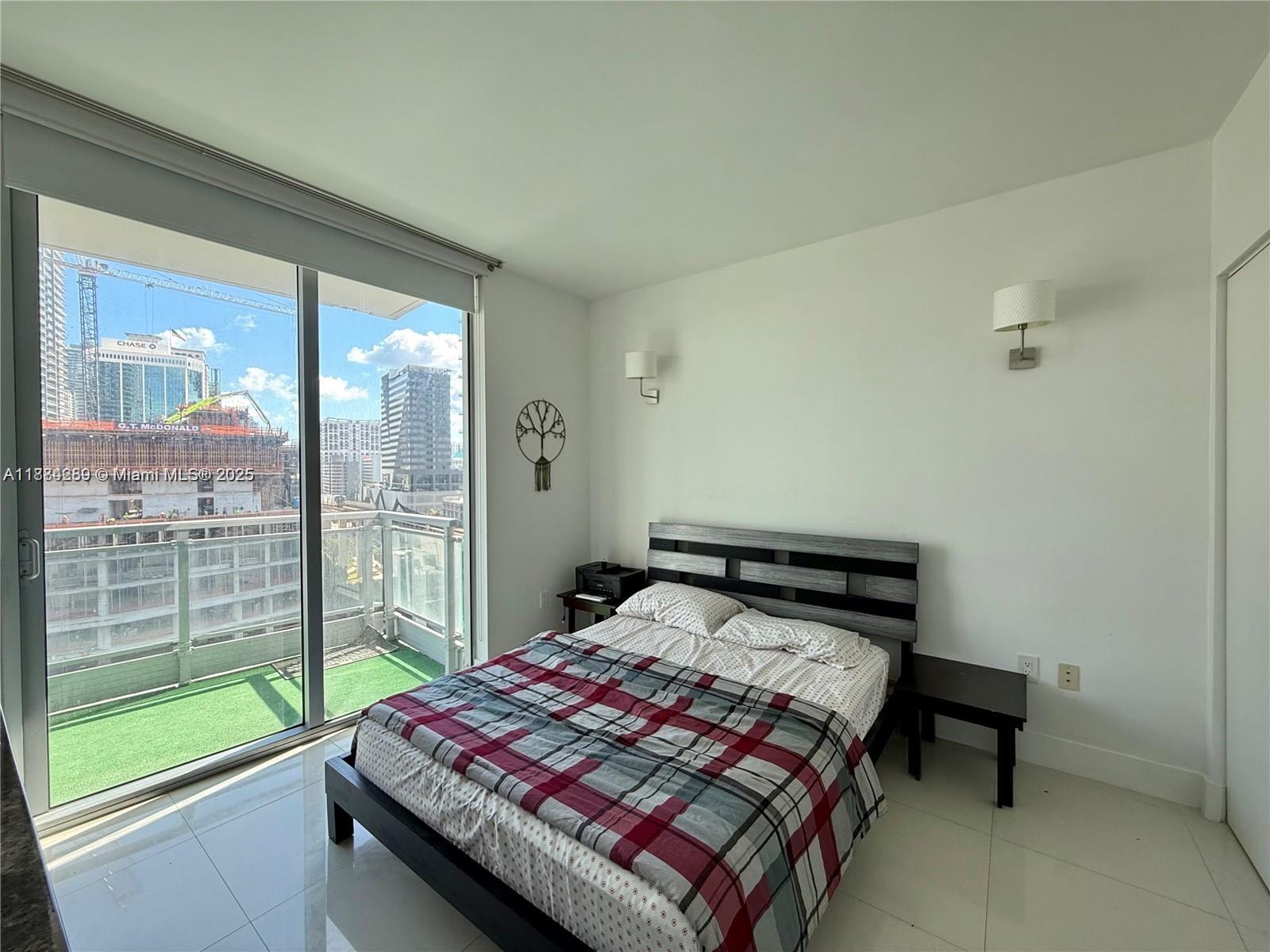 92 Southwest 3rd Street, Unit 1104 Miami, FL 33130 - Photo 9 of 17 a bedroom with a bed and glass door