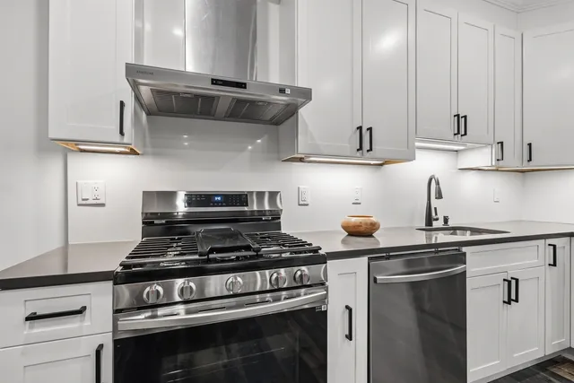 a kitchen with granite countertop a stove and a white cabinets