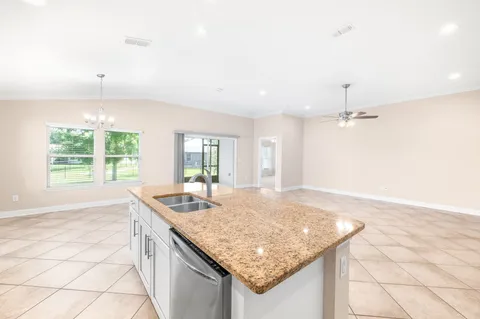 an empty room with kitchen island and natural light