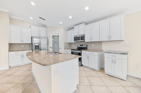 a kitchen with kitchen island granite countertop white cabinets white stainless steel appliances with a sink and dishwasher