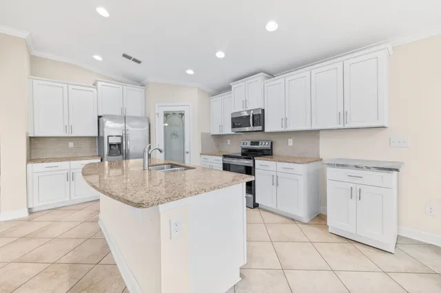 a kitchen with kitchen island granite countertop white cabinets white stainless steel appliances with a sink and dishwasher