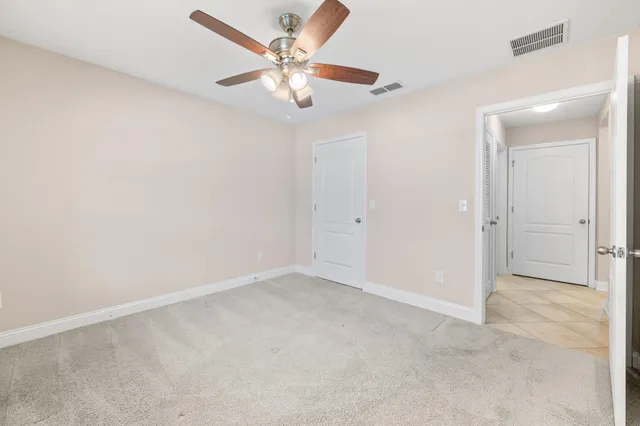 an empty room with a chandelier fan and closet area
