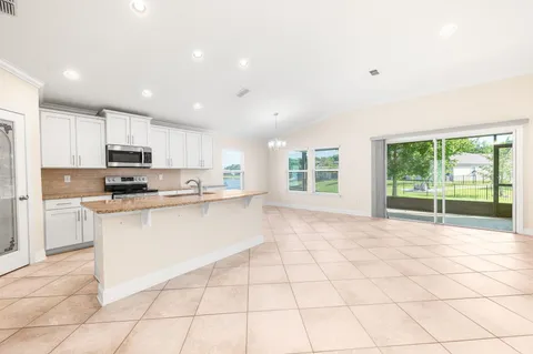 a large white kitchen with a stove a sink a microwave and a counter top space