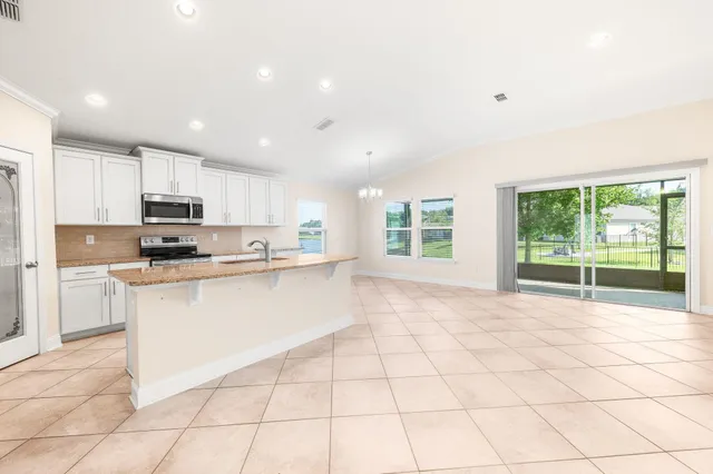 a large white kitchen with a stove a sink a microwave and a counter top space