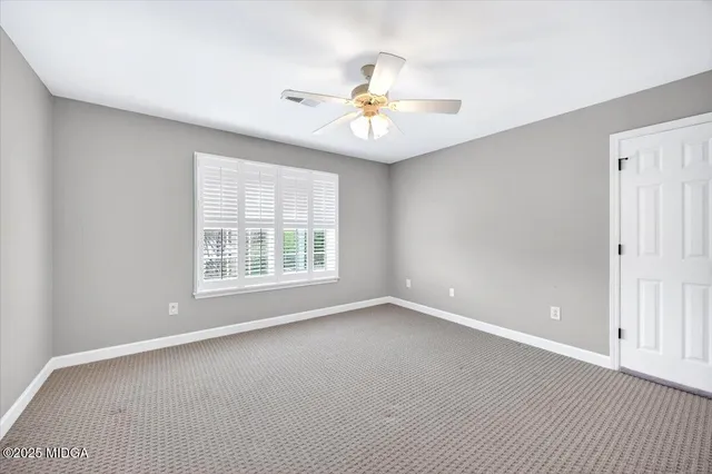 a view of an empty room with chandelier fan and a window