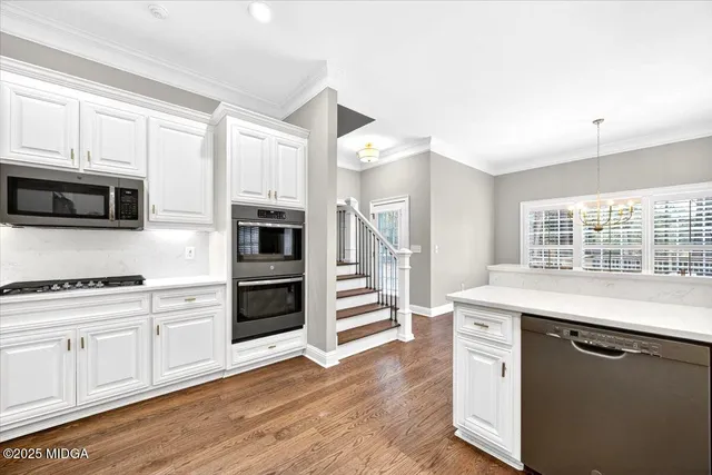 a kitchen with stainless steel appliances white cabinets and wooden floors