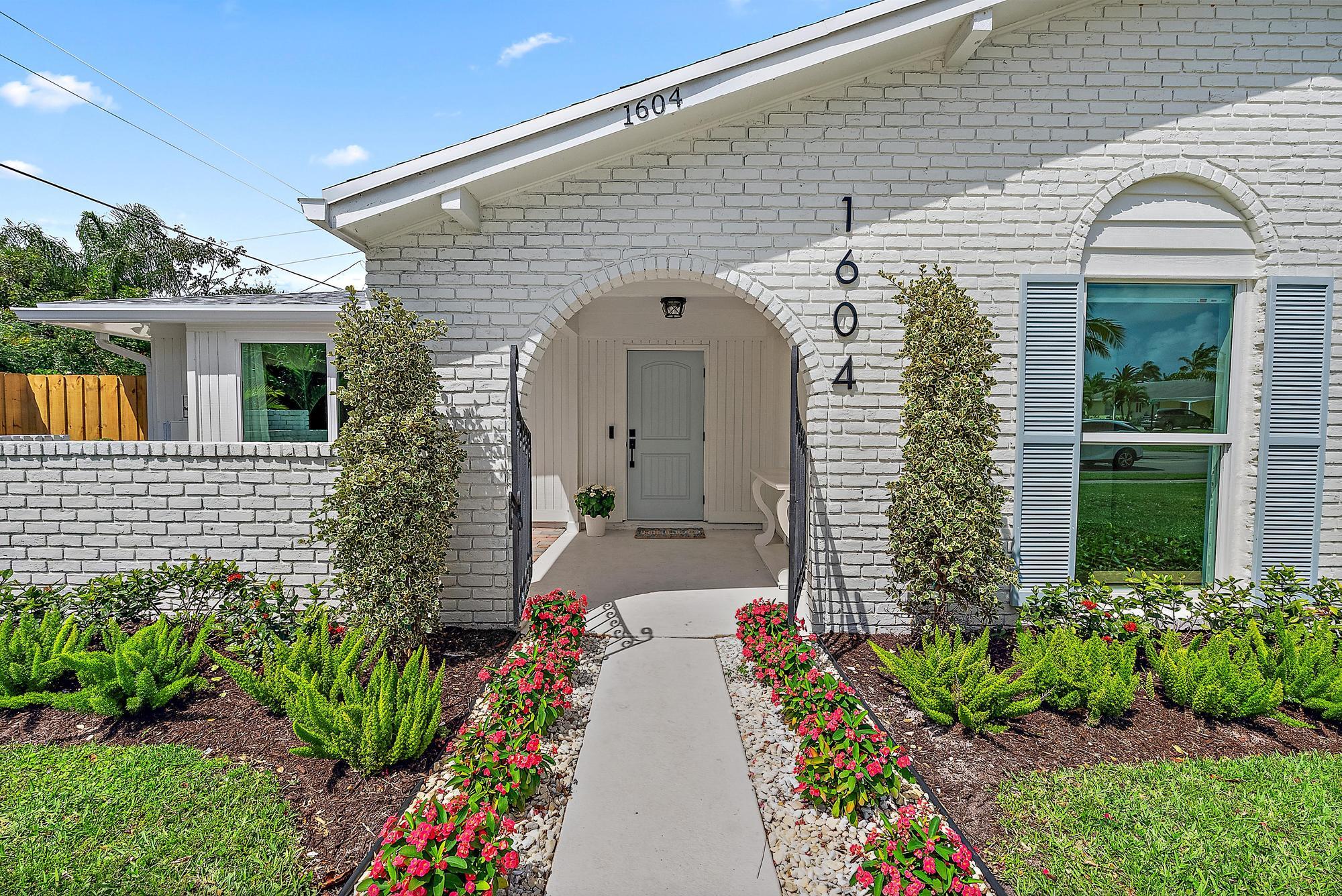 1604 Seabrook Road Tequesta, FL 33469 - Photo 2 of 42 a front view of a house with a garden