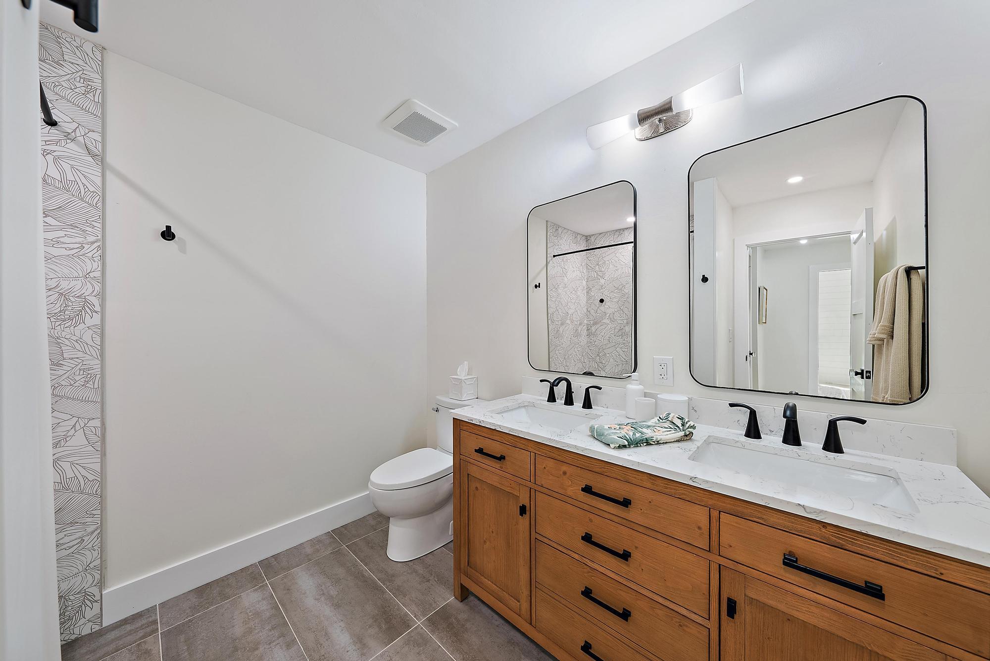 1604 Seabrook Road Tequesta, FL 33469 - Photo 22 of 42 a bathroom with a double vanity sink toilet and a mirror