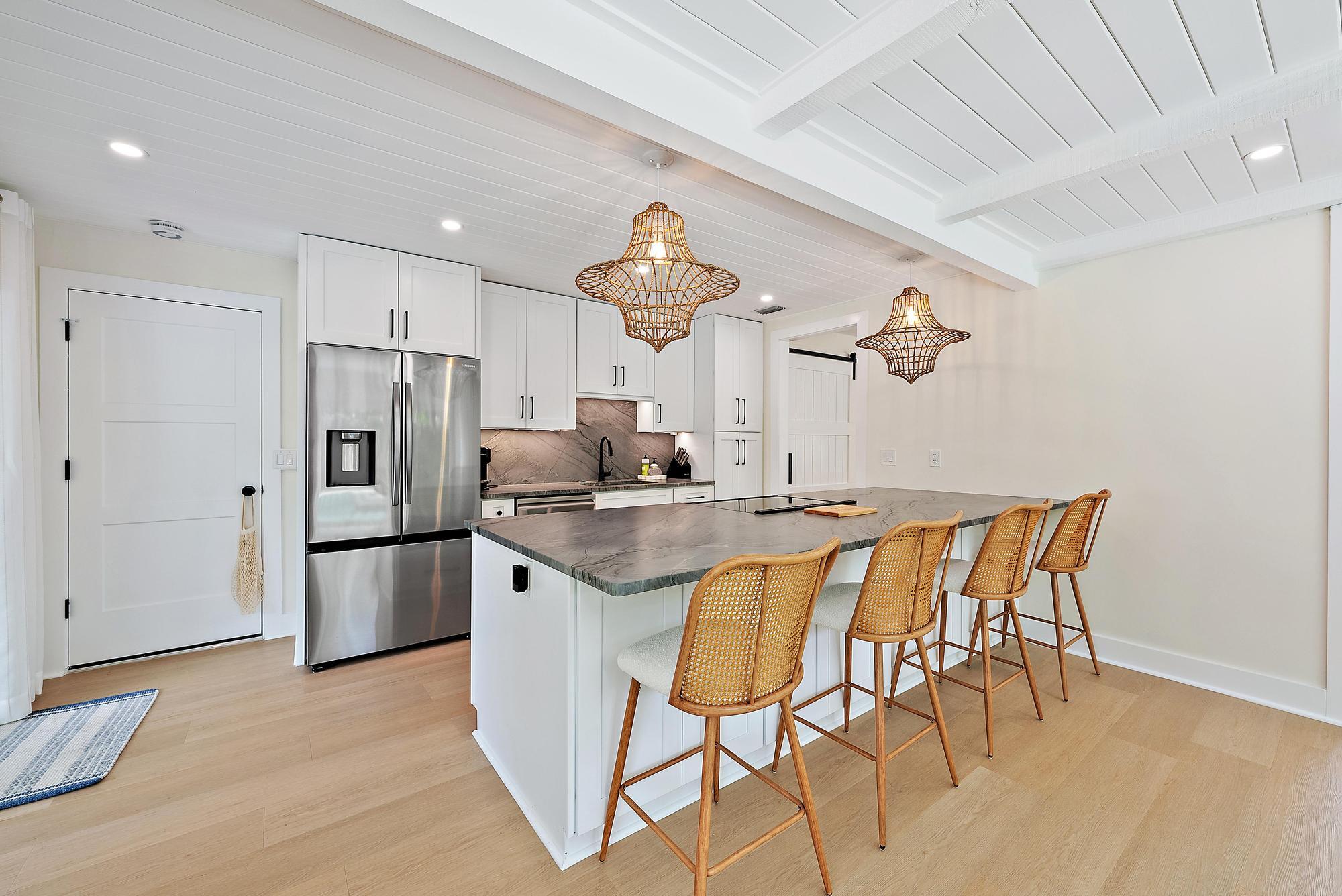 1604 Seabrook Road Tequesta, FL 33469 - Photo 10 of 42 a kitchen with stainless steel appliances granite countertop a kitchen island a stove a refrigerator and white cabinets with wooden floor