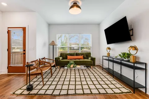 a living room with furniture a flat screen tv and a floor to ceiling window