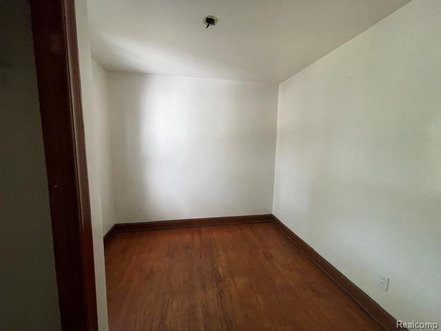 8930 Wayne Road Romulus, MI 48174 - Photo 13 of 18 Hardwood flooring, painted walls, ceiling light fixture, and wood trim
