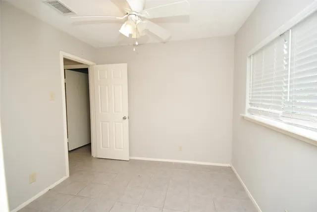 an empty room with a window and a fan