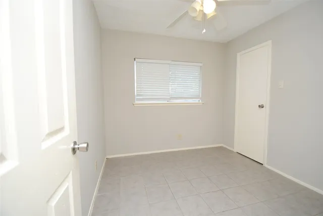 an empty room with a ceiling fan and window