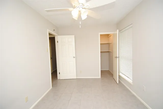 an empty room with a ceiling fan and a window