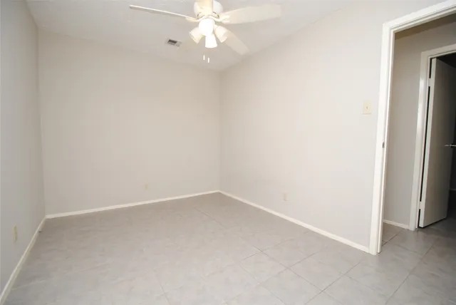 an empty room with a fan & a window