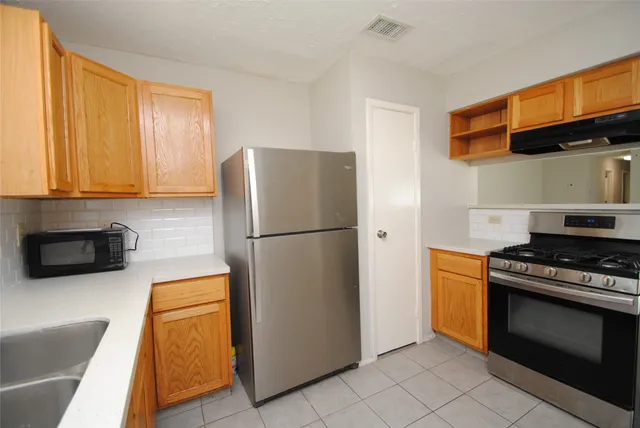 a kitchen with stainless steel appliances granite countertop a refrigerator a stove a sink and dishwasher