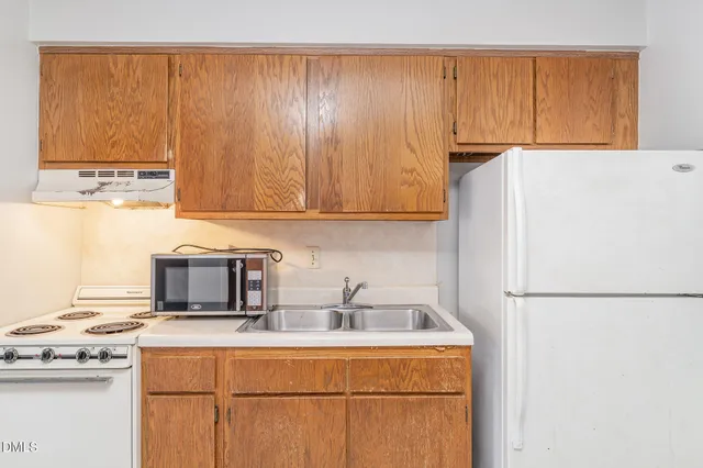 a kitchen with stainless steel appliances granite countertop a refrigerator a stove a sink and white cabinets