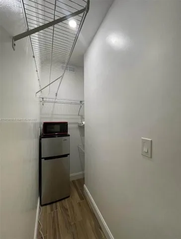 a kitchen with a refrigerator and wooden floor