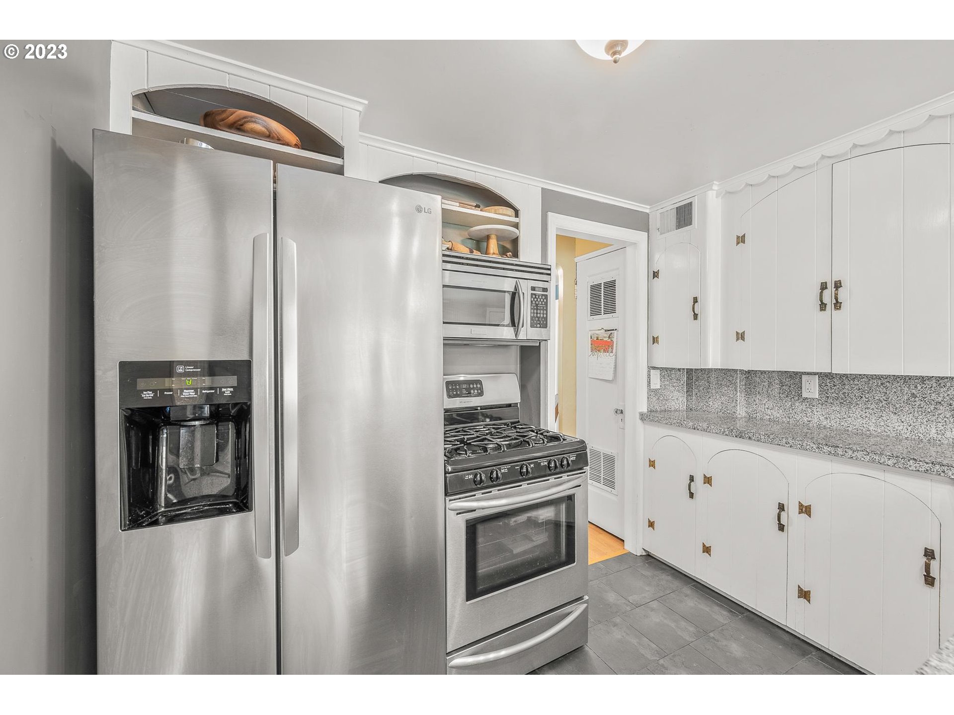4052 Southwest Huber Street Portland, OR 97219 - Photo 16 of 48 a kitchen with stainless steel appliances a refrigerator a stove and white cabinets