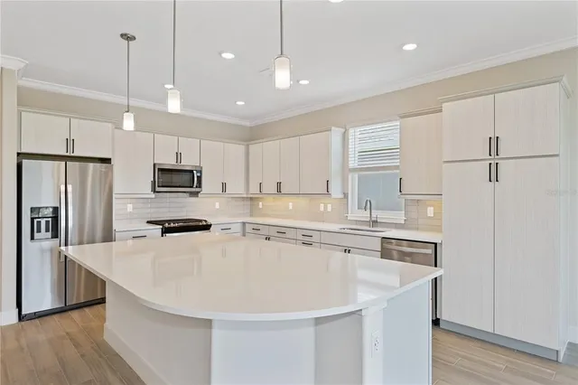 a kitchen with kitchen island a sink stainless steel appliances and refrigerator