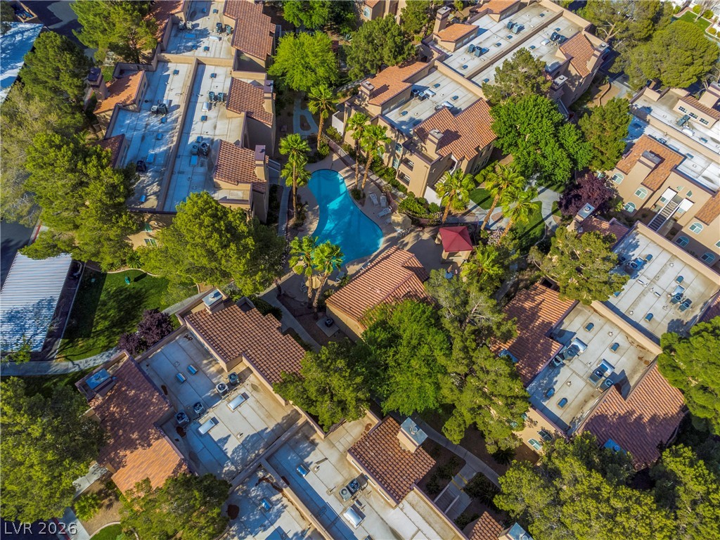 9325 West Desert Inn Road, Unit 260 Las Vegas, NV 89117 - Photo 3 of 4 An aerial perspective reveals a community featuring a shimmering outdoor pool amidst lush trees and residential buildings.