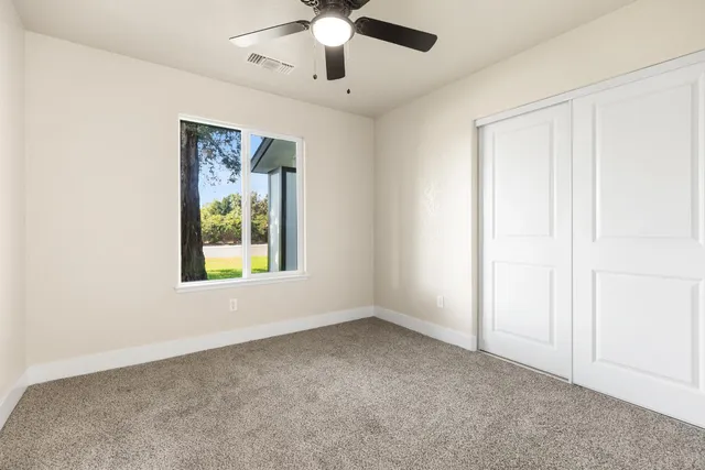 an empty room with a window and a fan