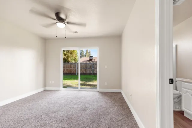 an empty room with windows and fan