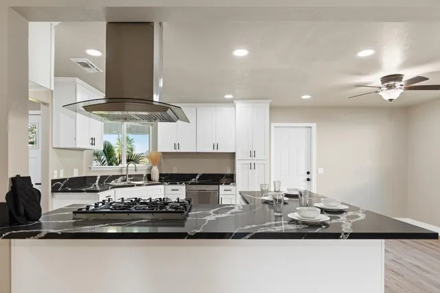 a kitchen with stainless steel appliances kitchen island granite countertop a sink a stove and a wooden floors