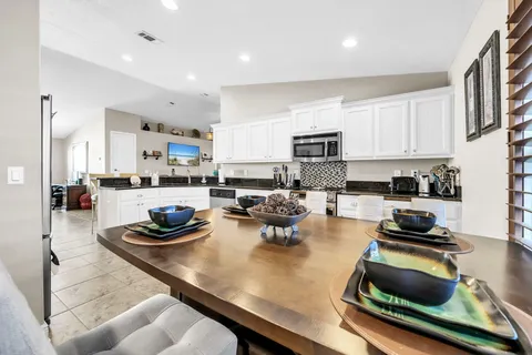 a kitchen with a sink a stove and chairs with wooden floor