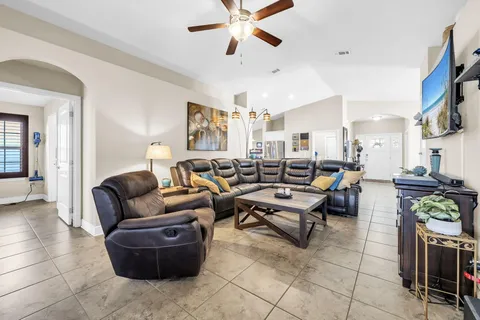 a living room with furniture kitchen view and a chandelier