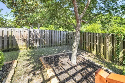 a view of a backyard with wooden fence and a large tree