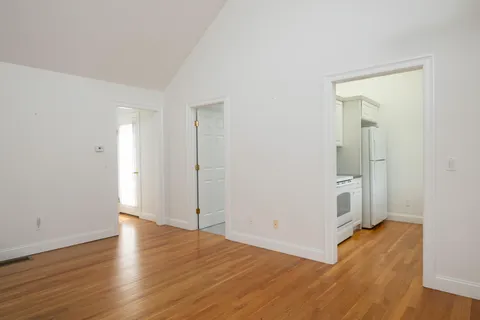 an empty room with wooden floor & windows and bathroom