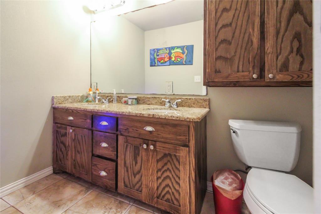 1001 Sandy Ridge Road Scurry, TX 75158 - Photo 22 of 35 Double wood-finish vanity with granite-style countertop, dual sinks, and under-cabinet storage