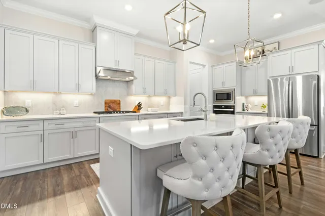 a kitchen with stainless steel appliances granite countertop a sink a stove a refrigerator and island with wooden floor