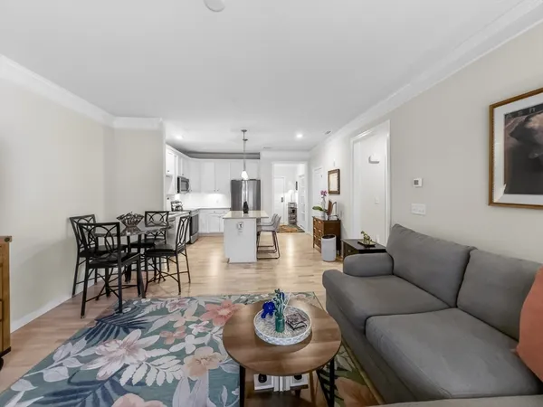 a living room with furniture kitchen area and a chandelier