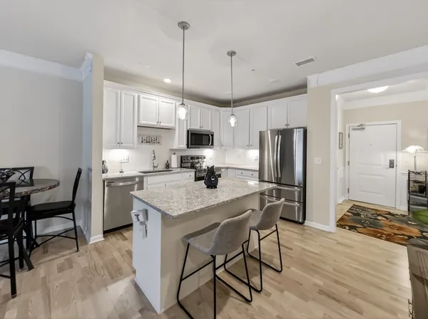 a kitchen with stainless steel appliances granite countertop a stove a refrigerator a kitchen island a sink cabinets and a refrigerator