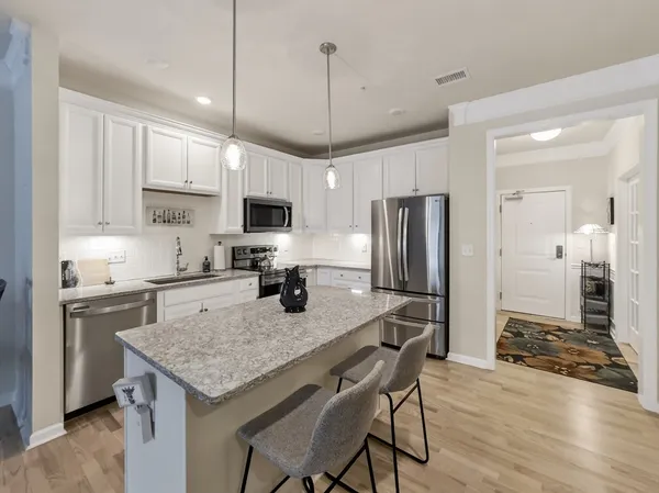 a kitchen with granite countertop a stove a sink a refrigerator a center island and cabinets