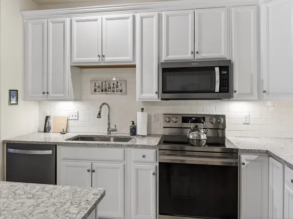 a kitchen with granite countertop white cabinets and stainless steel appliances