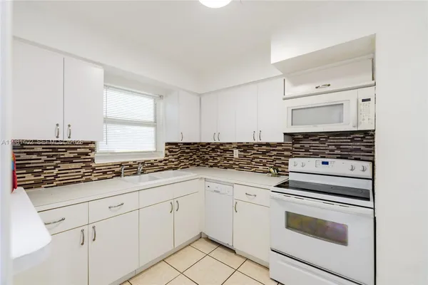 a kitchen with granite countertop white cabinets and white appliances