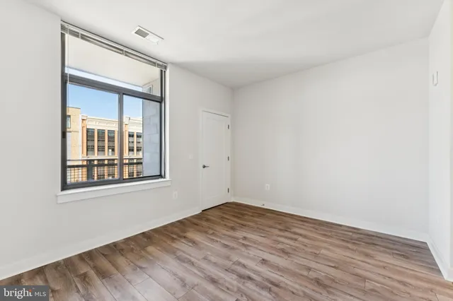 a view of empty room with wooden floor and fan