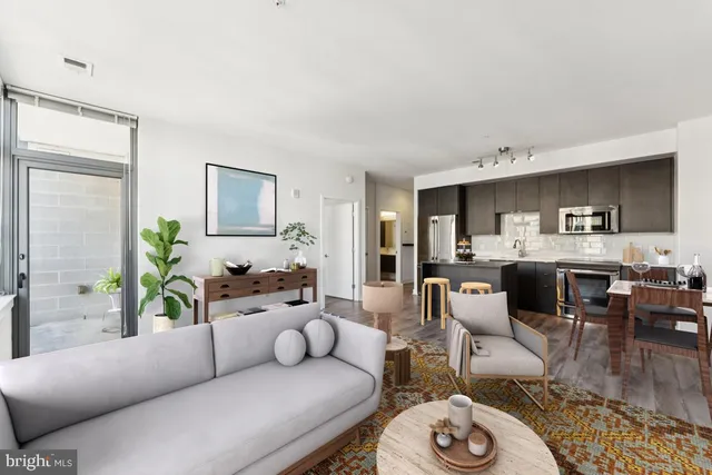 a living room with furniture kitchen view and a window