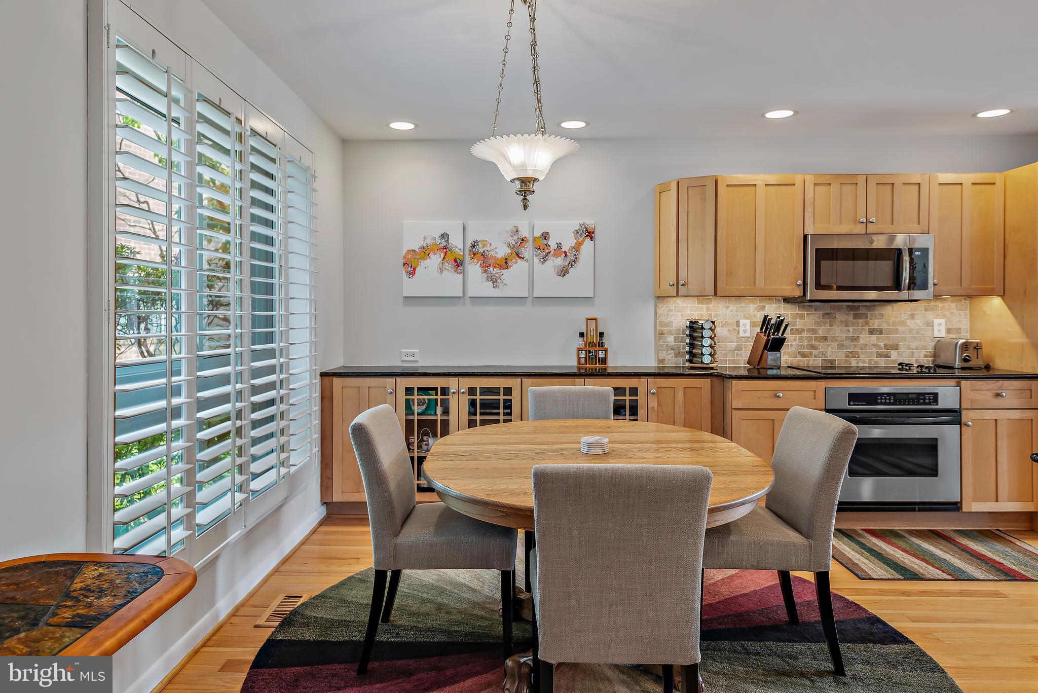 7261 Dockside Lane Columbia, MD 21045 - Photo 24 of 68 a kitchen with stainless steel appliances granite countertop a stove a sink a microwave a dining table and chairs with wooden floor