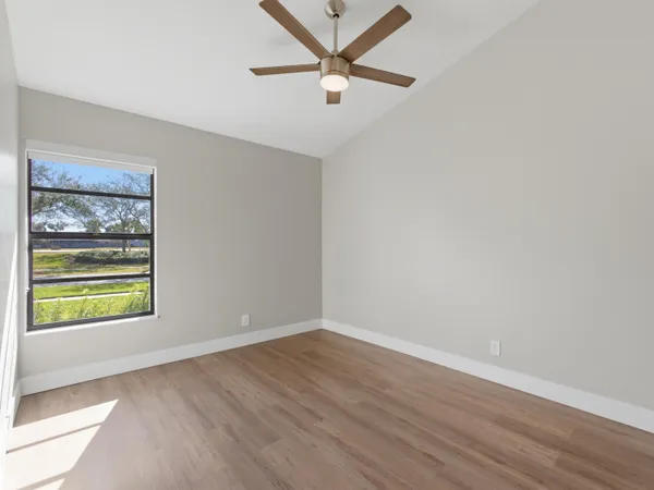 an empty room with a window and a ceiling fan