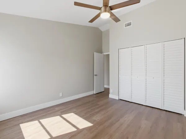 an empty room with wooden floor closet and windows