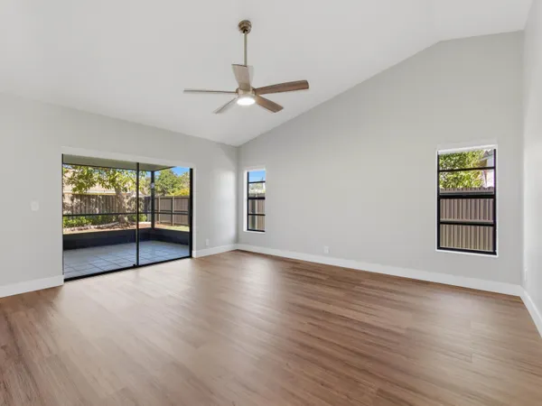 a view of an empty room with wooden floor and fan