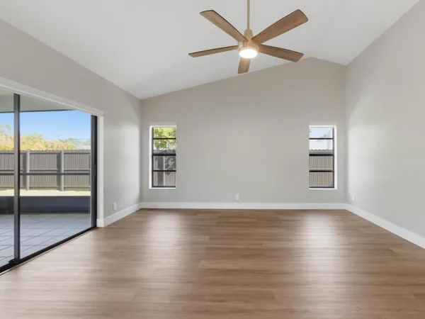 an empty room with wooden floor closet and windows